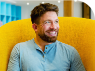 Man in blue shirt sitting in yellow chair and smiling